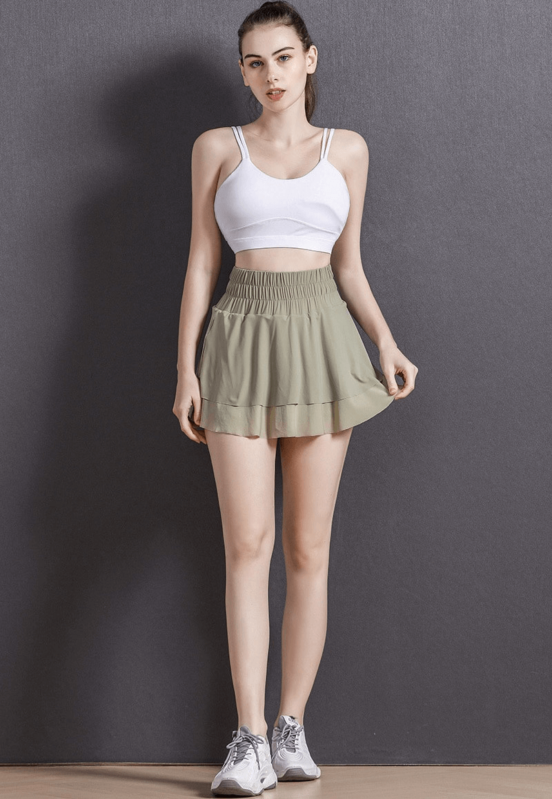 Woman wearing a high waist tennis skirt with hidden pockets, ideal for sports like tennis, yoga, and fitness, in a breathable design.